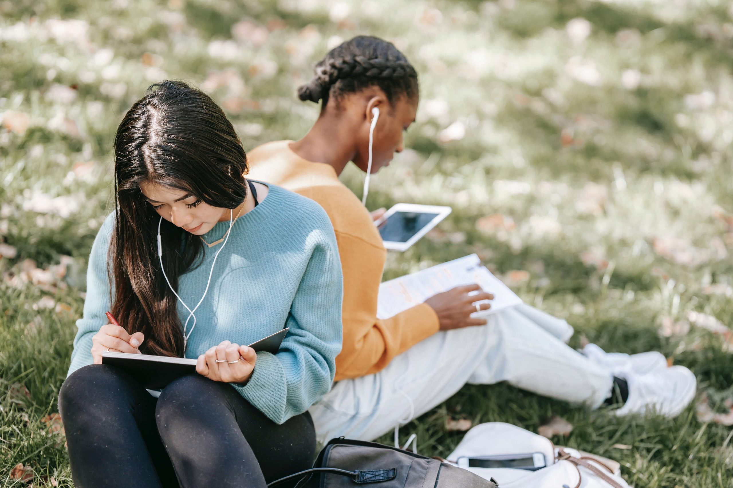 two college girls studying and listening to music in the forest